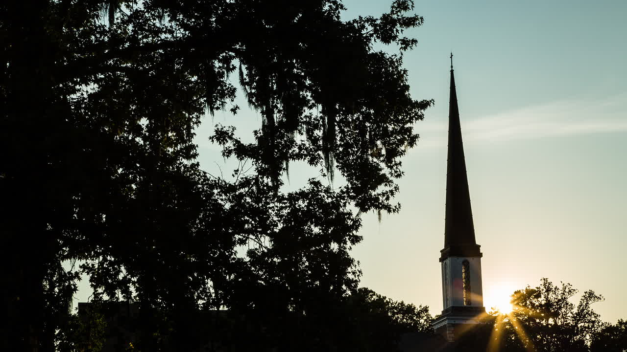 Time lapse of the sun setting behind a church steeple