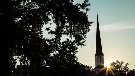 time lapse of the sun setting behind a church steeple