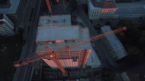 aerial top down shot of the skyscraper building in the process of construction. in the background working crane and modern city.