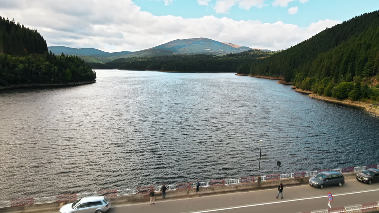 Aerial drone view of the Oasa Dam in Romania. Carpathian mountains, hills with lush forest, multiple visitors