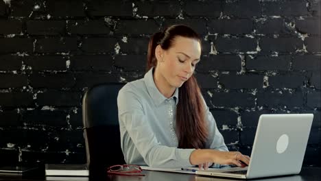 una mujer de negocios con una computadora portátil escribe en un documento en su oficina