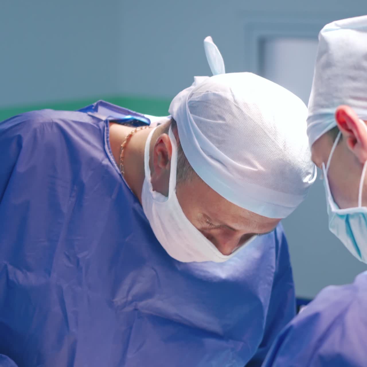 Surgeons during operation. Two doctors in blue medical uniform and masks concentrated on a surgery process in the operating room.