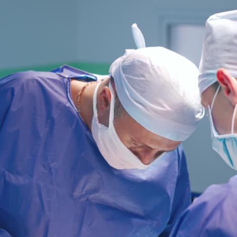surgeons during operation. two doctors in blue medical uniform and masks concentrated on a surgery process in the operating room.