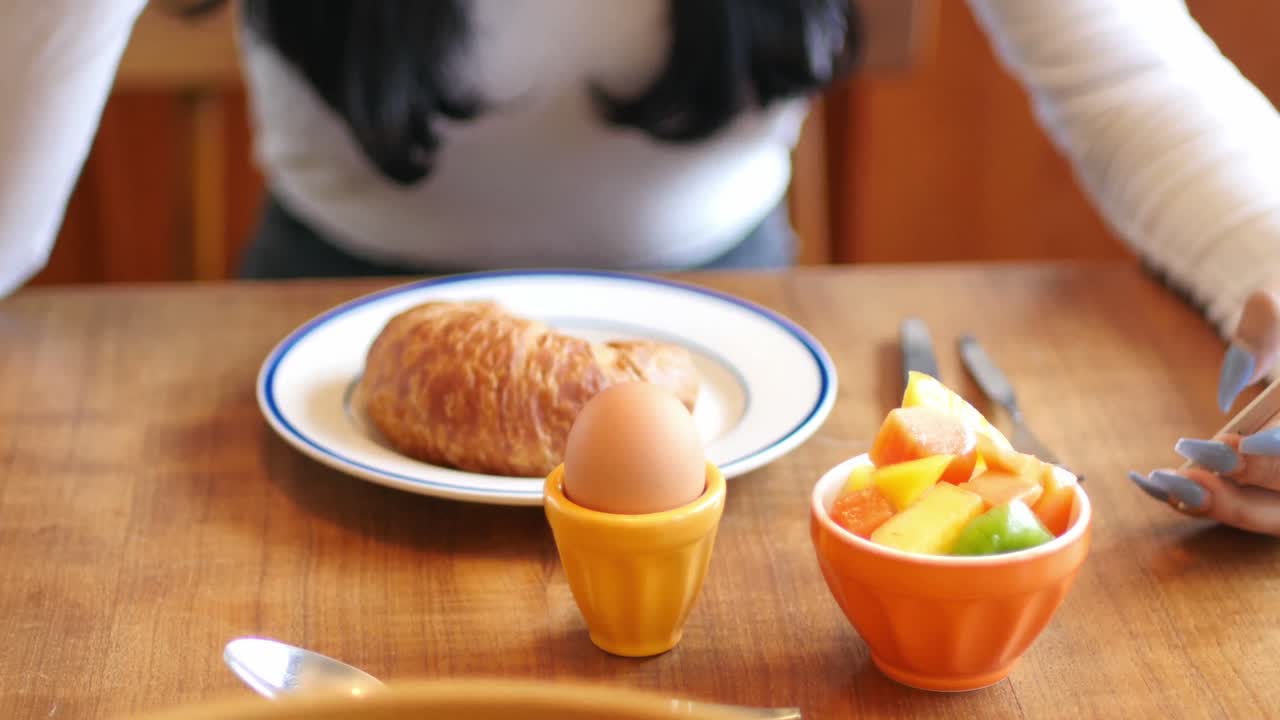 아침 식사를 하는 동안 휴대 전화 를 사용하는 여자