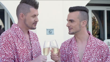 gay couple celebrating with champagne on a hotel balcony