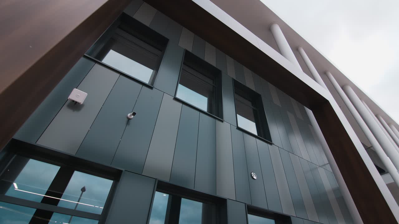 edificio nuevo con fachada oscura y postes en el sitio de construcción