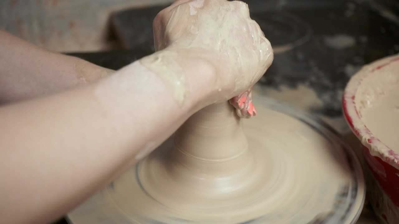 una mujer alfarera hace platos de arcilla. una mujer hace una jarra en la rueda de un alfarero