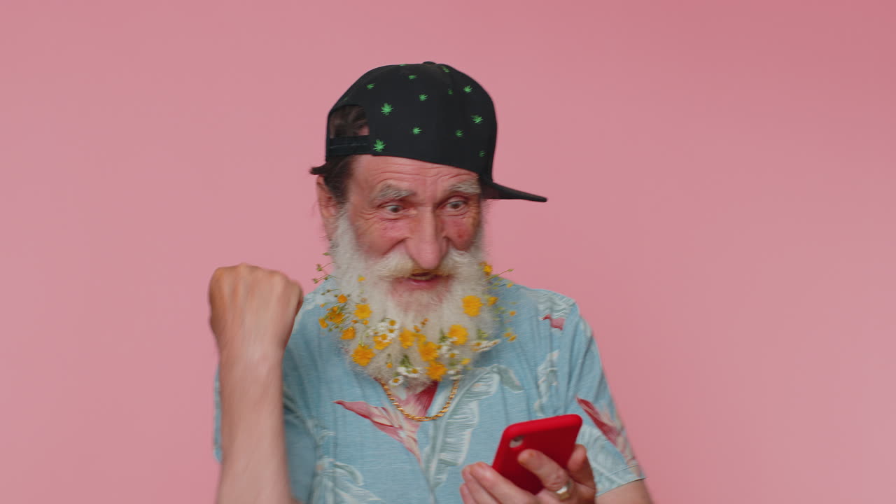 feliz emocionado anciano uso de teléfono móvil decir wow sí descubrió gran gran noticia ganar haciendo el gesto ganador