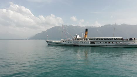 Dynamische-Luftaufnahme-Eines-Wunderschönen-Kreuzfahrtschiffes,-Das-An-Einem-Sonnigen-Sommertag-über-Den-Genfersee-Fährt