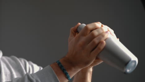 young male shaking a cocktail in a mixer at home in the kitchen