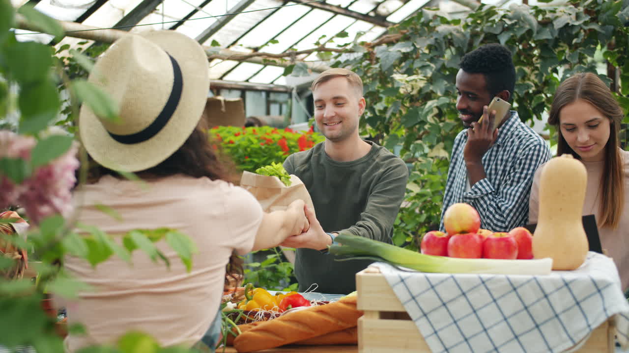 People shopping at a farmers market in a greenhouse
