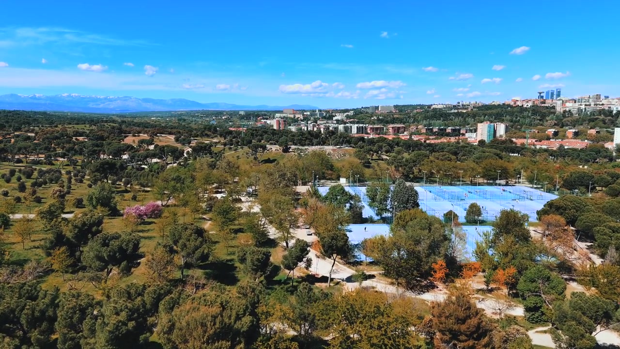 Vista aérea amplia de Casa de Campo con el horizonte de Madrid y montañas