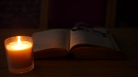 un par de anteojos en un viejo libro antiguo en una habitación oscura iluminada por velas