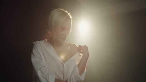 close-up view of caucasian young female model posing in the dark studio with smoke while the photographer taking shots of her