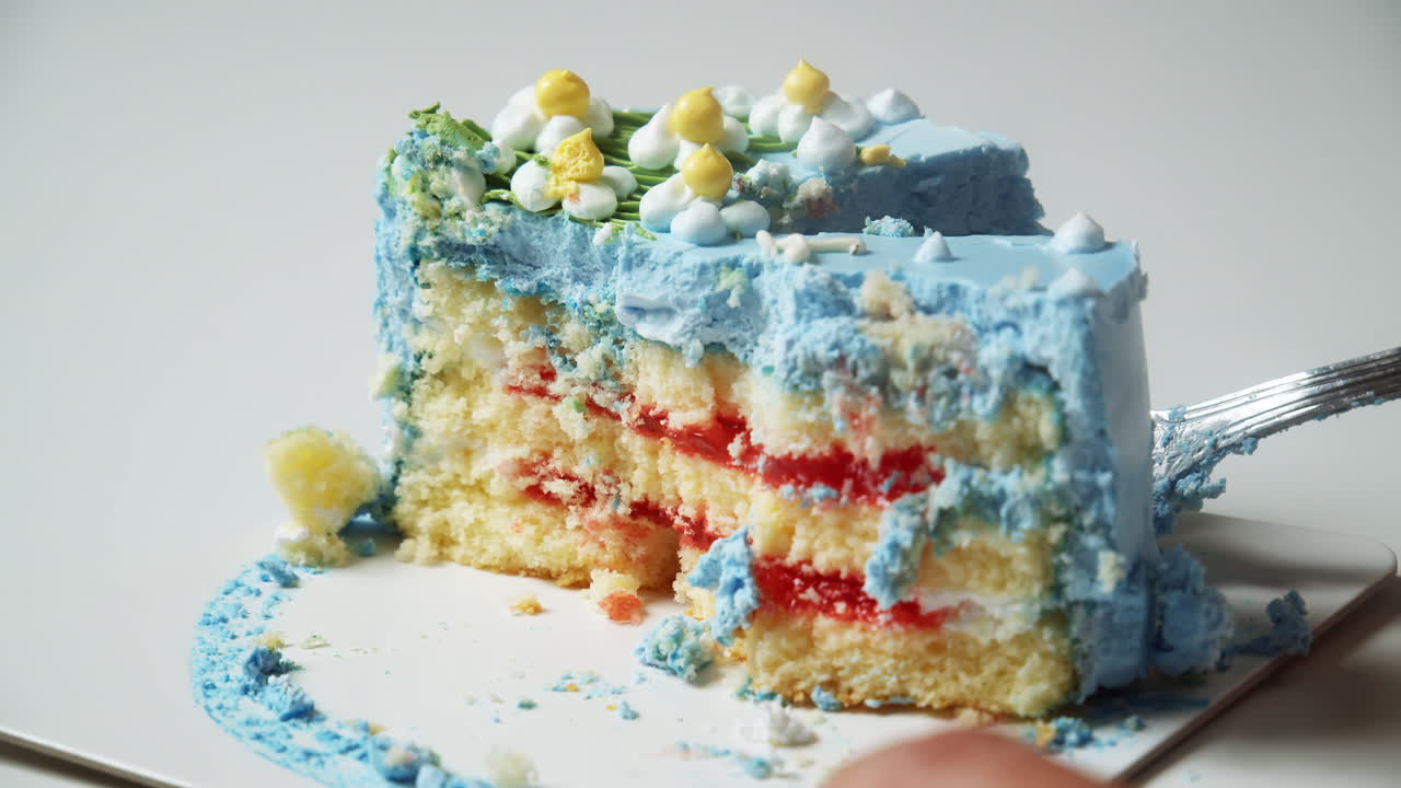 Slicing a fluffily layered cake, filled with decadent strawberry filling, topped with a deliciously soft, sweet, and delectable blue buttercream frosting