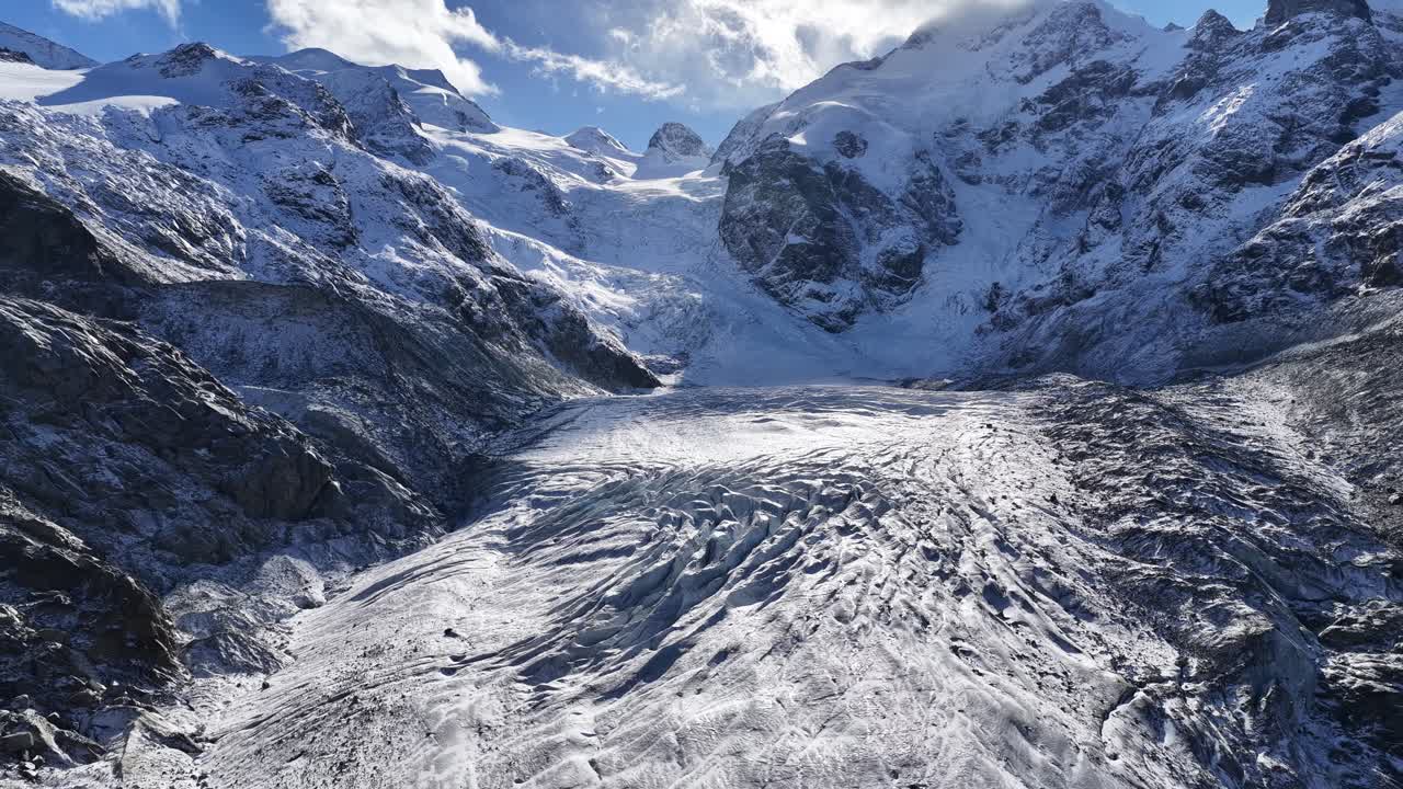 A stunning wide-angle view of the Morteratsch Glacier in Kanton Graubünden, Schweiz. The massive, fractured ice tongue flows dramatically between dark, rugged mountain walls