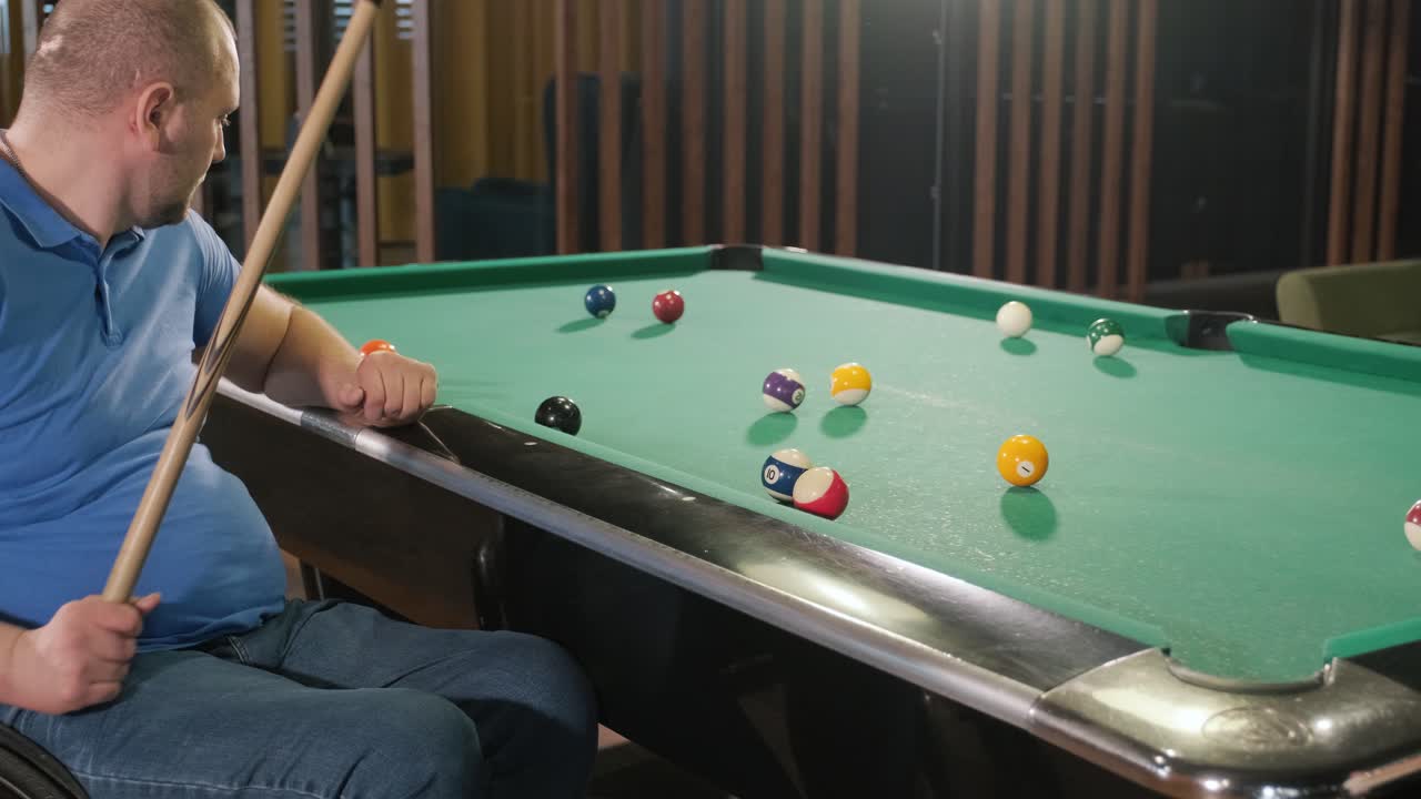 Adult men with disabilities in a wheelchair play billiards in the club