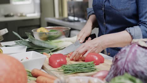 Midsection-of-senior-caucasian-woman-chopping-red-pepper-in-kitchen,-slow-motion