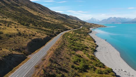 Picturesque-aerial-backward,-van-drives-along-blue-lake-Pukak-in-New-Zealand