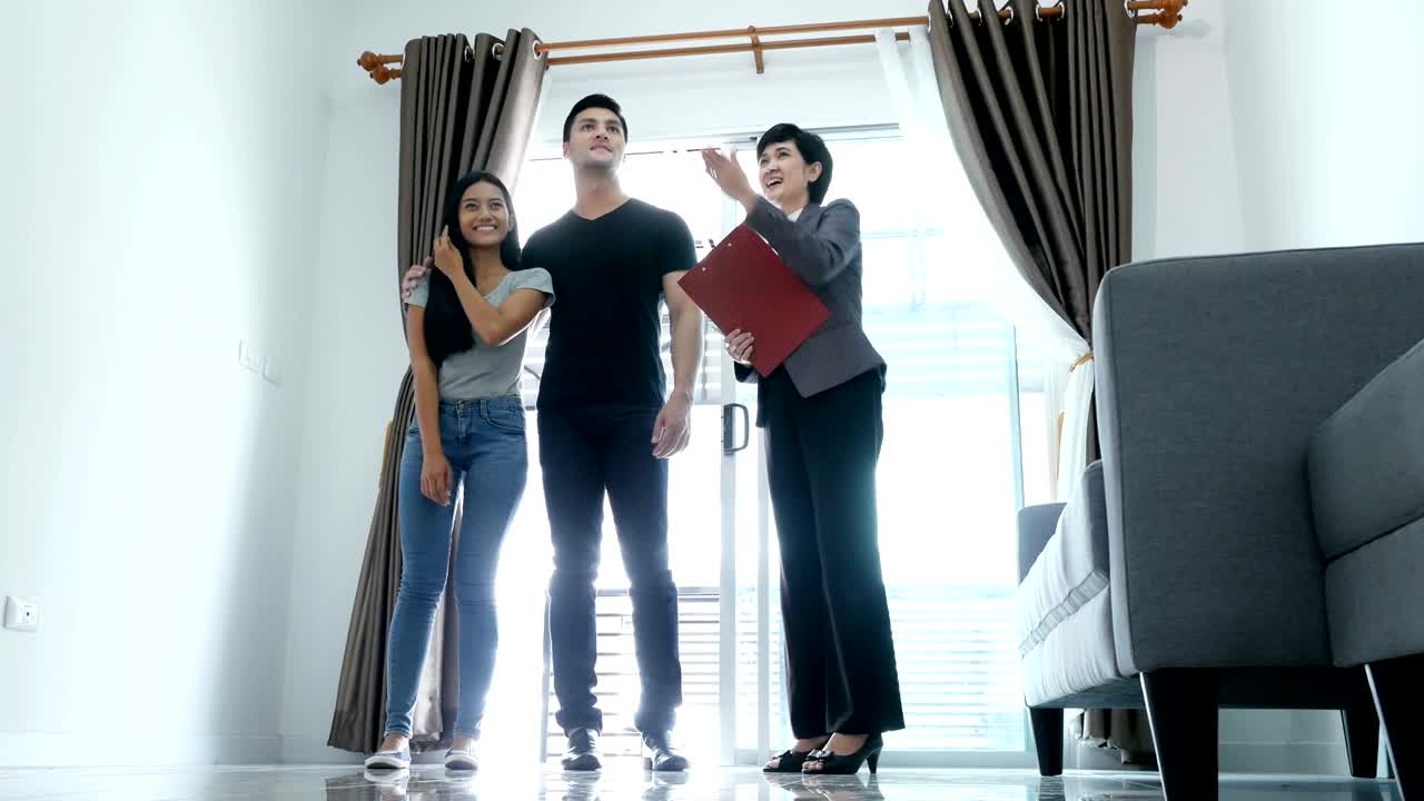 새로운 집을 구입하거나 임대하려는 젊은 부부. 전문 부동산 에이전트가 고객에게 현대적인 집을 제시합니다. 4k 해상도.