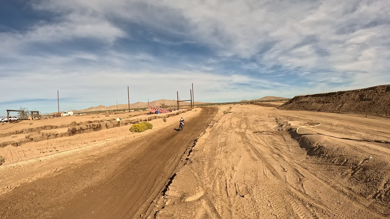una carrera de motocicletas a lo largo de una pista de carreras de motocross en un gran salto y a través de giros - vista de drones en primera persona