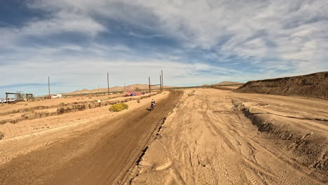 Una-Carrera-De-Motocicletas-A-Lo-Largo-De-Una-Pista-De-Carreras-De-Motocross-En-Un-Gran-Salto-Y-A-Través-De-Giros---Vista-De-Drones-En-Primera-Persona