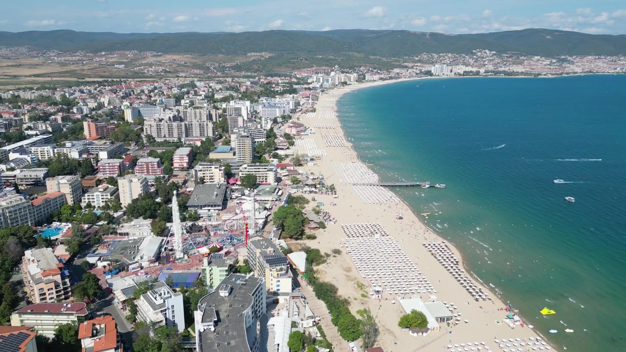 Bulgaristan'daki Sunny Beach sahil şeridi boyunca uzun kumlu plajın, otellerin ve Karadeniz sularının manzaralarıyla akıcı drone ileri uçuşu