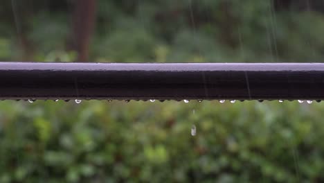 raindrops fall to the balcony railing and slide down during heavy thunderstorm