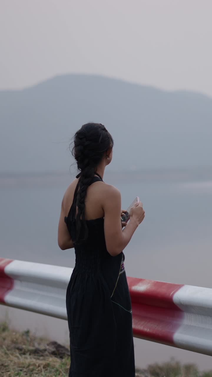 Woman looking at her phone by the lake