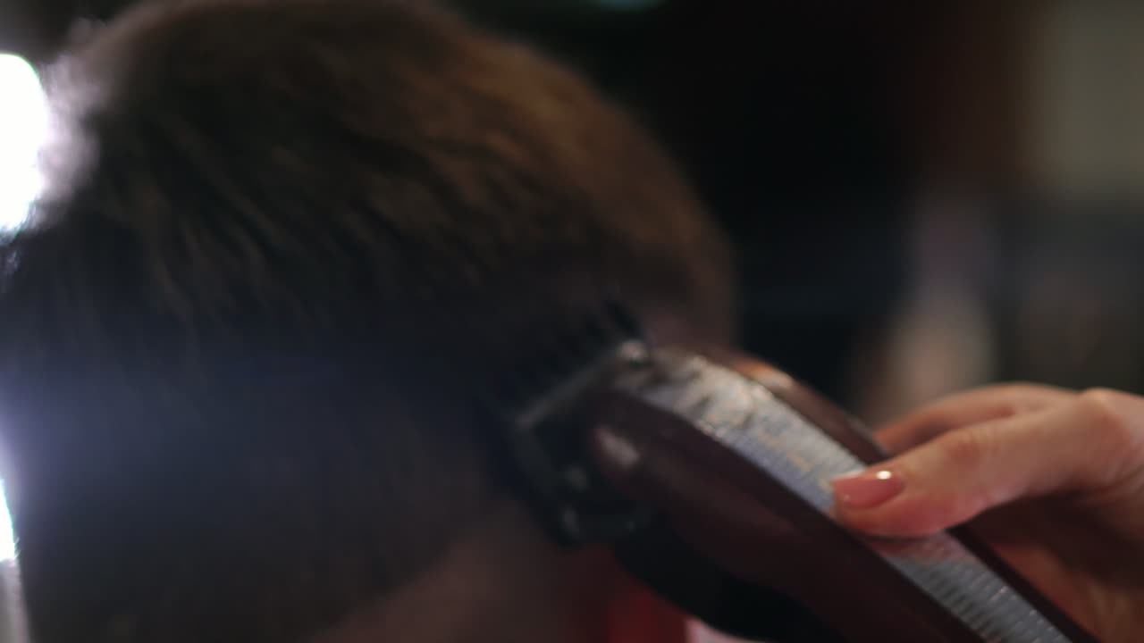 Rear view of man client visiting haidresser and hairstylist in barber shop.