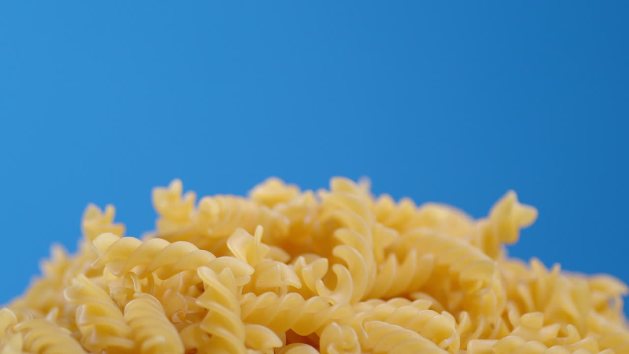 un montón de pasta de fusilli seco gira lentamente.