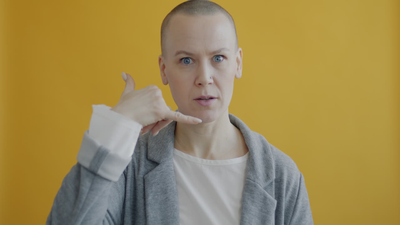 Woman making a phone gesture in front of a yellow background