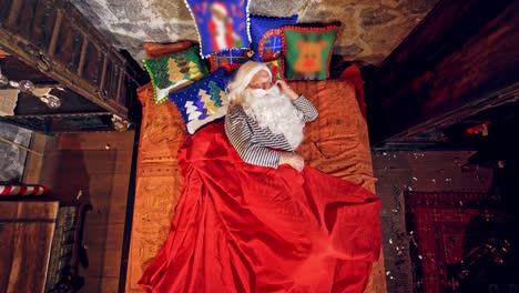 santa claus is sleeping in specially decorated room in his bed. he is holding his hand under his cheek. christmas concept close up video. christmas and new year is coming. aerial view. video from above.