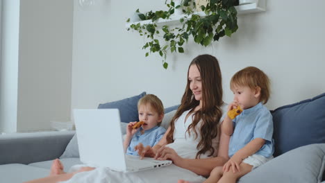 Una-Joven-Madre-Y-Dos-Hijos-Pequeños-Hacen-Compras-En-La-Tienda-En-Línea-Usando-Una-Computadora-Portátil