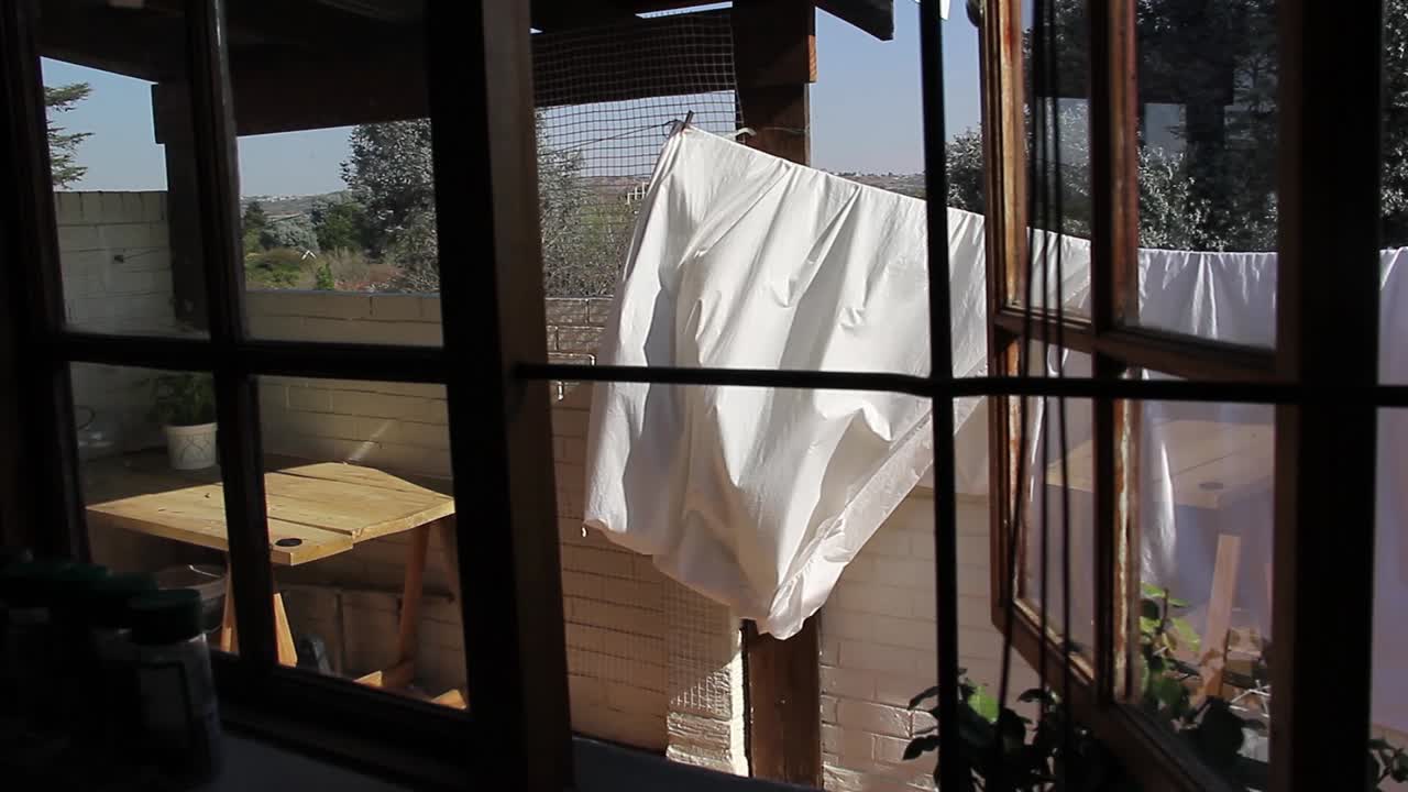 빨래줄 위의 침대보가 바람에 날린다