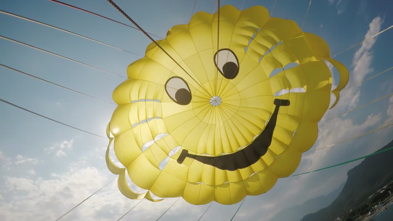 холодный желтый купол парашюта на фоне голубого неба и пробивающегося сквозь него солнца