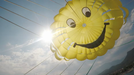 a cool yellow dome of the parachute against the blue sky and the sun poking through it