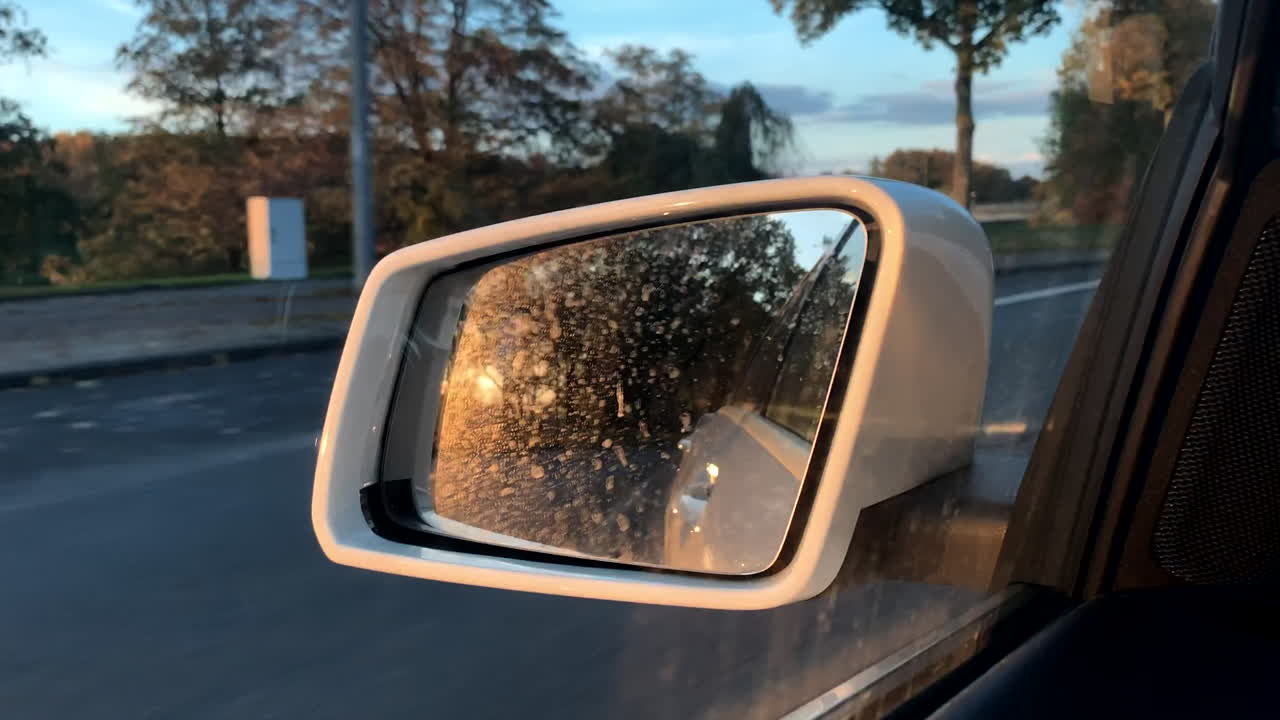 primer plano del reflejo de la puesta de sol en el espejo lateral del coche, estable
