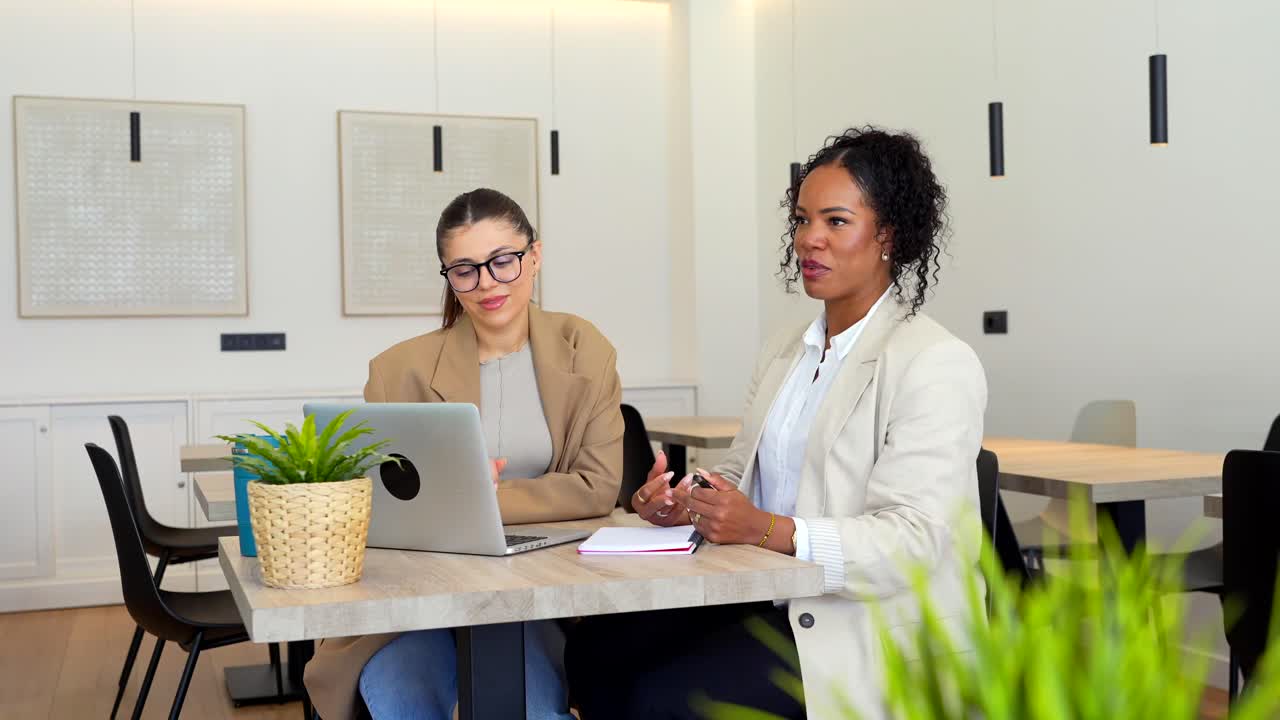 Two Businesswomen Collaborating at a Table with a Laptop