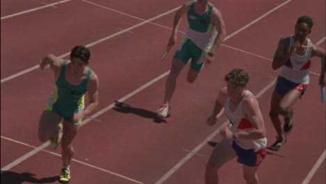 male runners pass the baton in a relay race