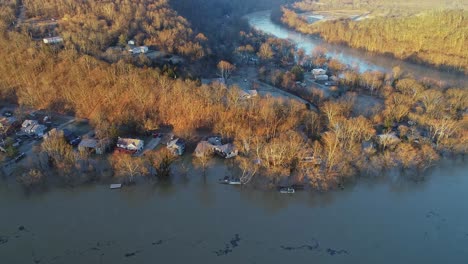 aerial top down view of deciduous forest with flooded riverfront homes in kentucky usa at sunset