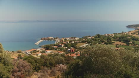 a breathtaking view of a small coastal village in greece, surrounded by green hills and deep blue sea.