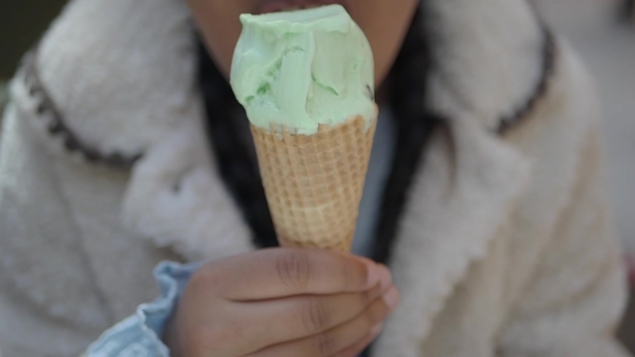 Giovane che gusta una pallina di gelato alla menta in un cono waffle