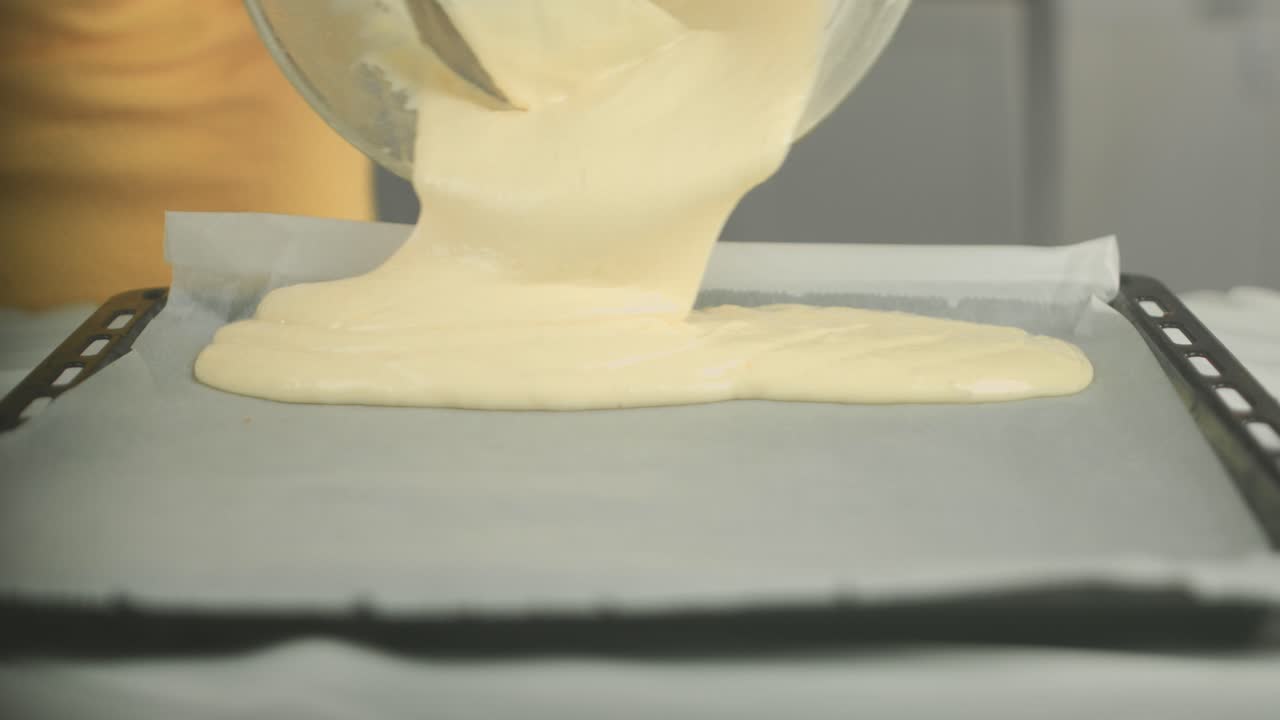 Close up of a cake dough being put on a baking plate with a backing sheet by a vegan chef