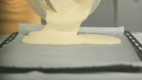 close up of a cake dough being put on a baking plate with a backing sheet by a vegan chef