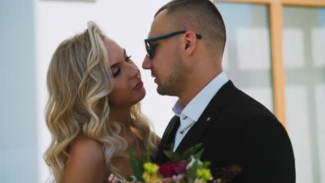 languid bride with bouquet looks at fiance on city street