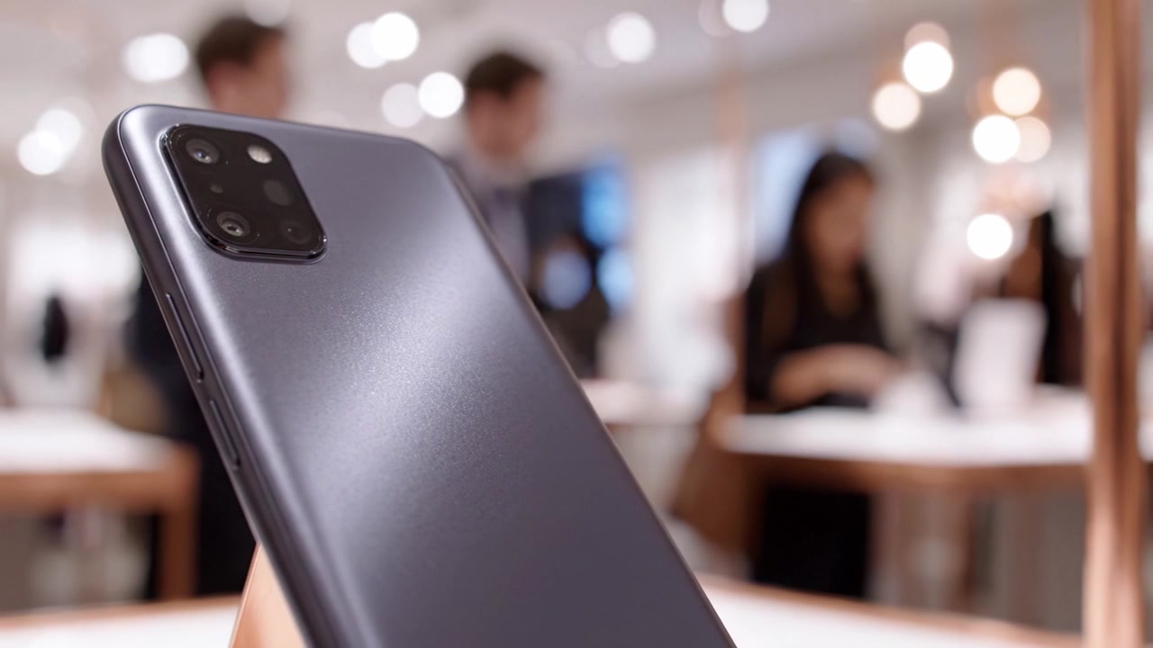 Elegantní prezentace smartphonu zdůrazňující moderní design a technologie, s rozmazaným maloobchodním pozadím poukazujícím na zapojení spotřebitelů a elektronické inovace