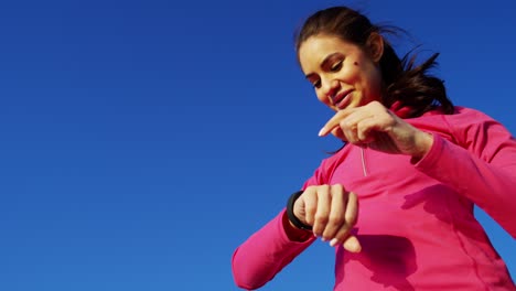 hispanic caucasian female stretching outdoors wearing smart watch