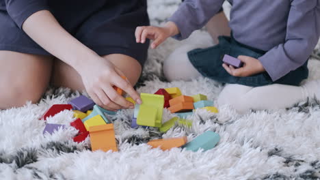 imágenes en cámara lenta de una madre y su hija construyendo bloques de juguete en una alfombra blanca