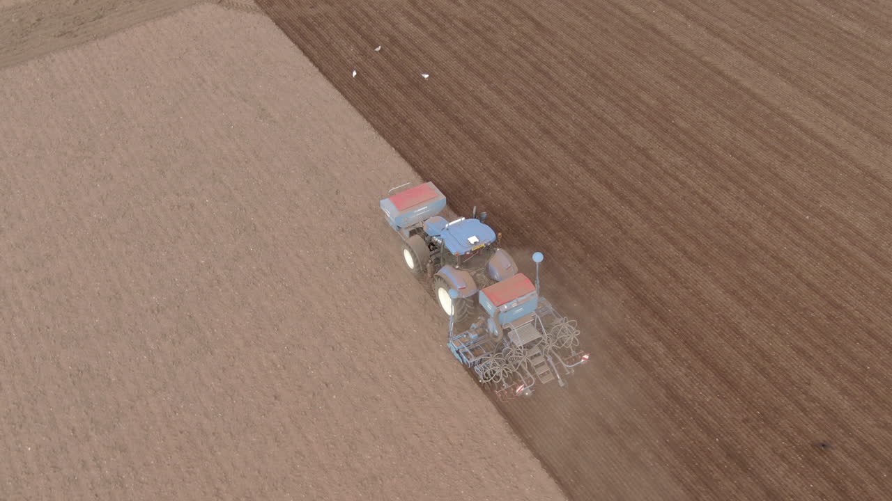 스코틀랜드 애버딘셔의 들판을 갈 때 트랙터의 공중 시계 방향 근접 추적 샷